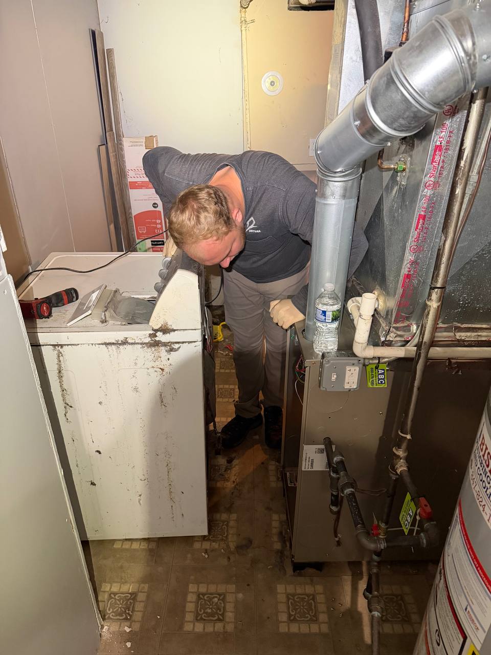 Technician working beside a washer and HVAC equipment