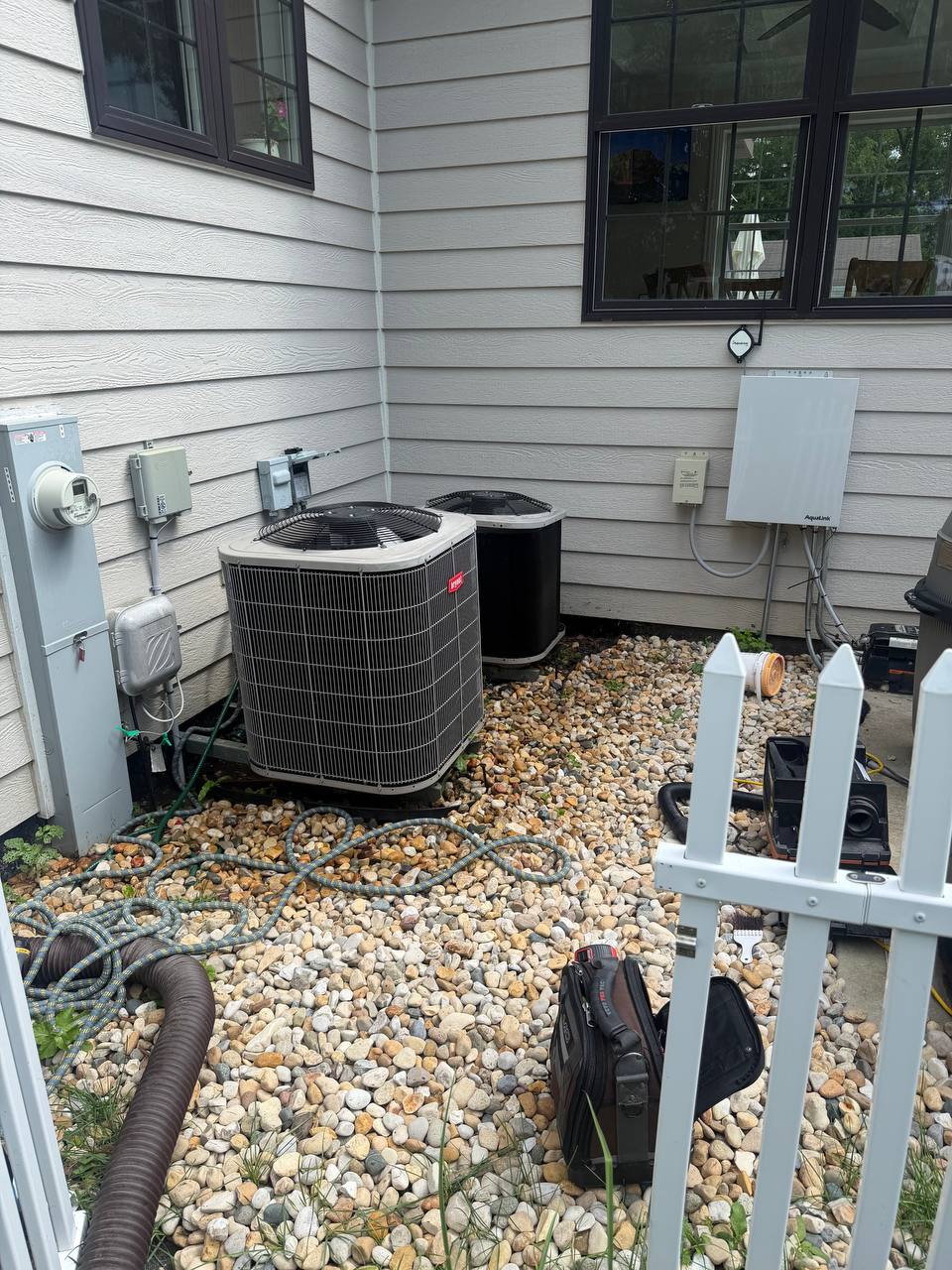 Two outdoor AC condenser units beside a home
